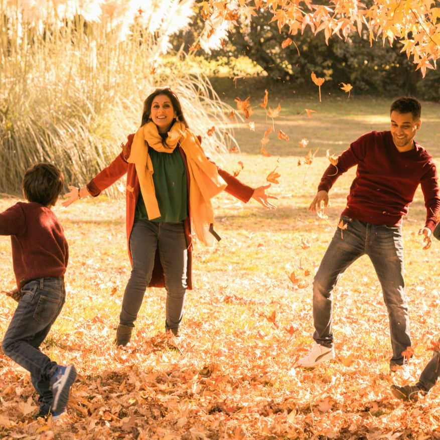 A family playing in autumn leaves